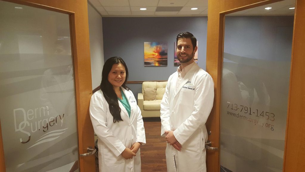 Woman and man in white coats in DermSurgery entryway.