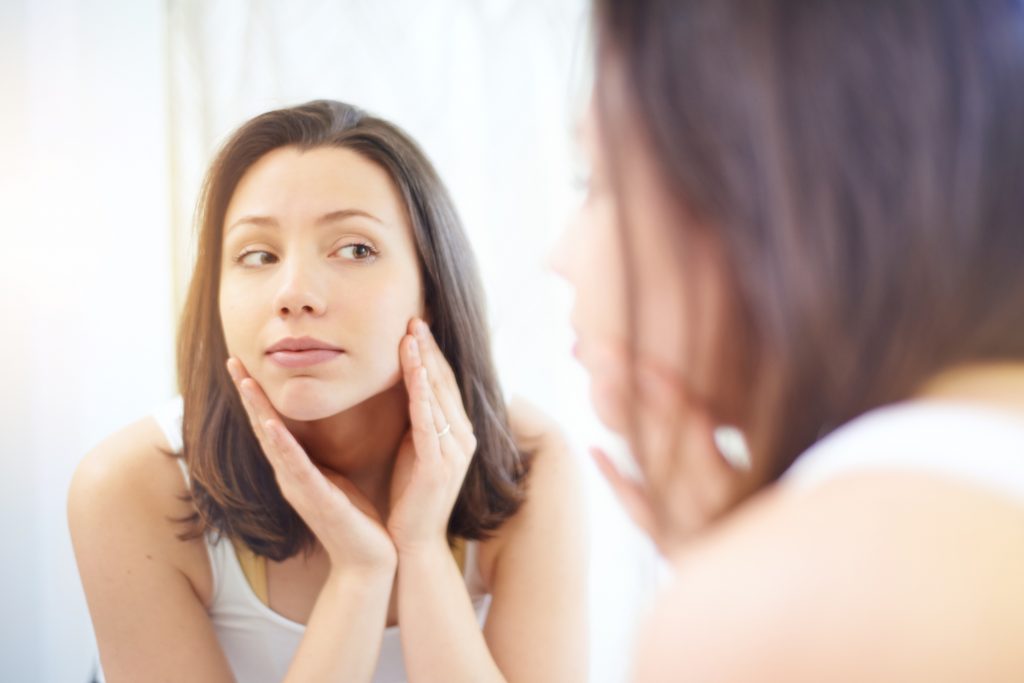 Woman examining her face in the mirror.