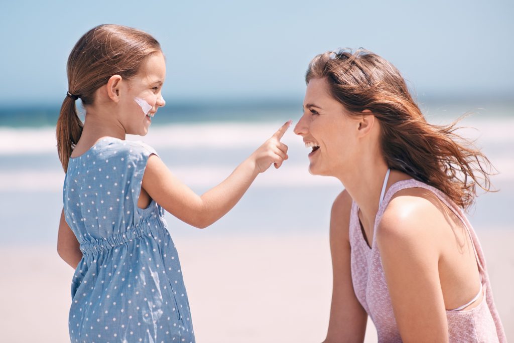 Mother and daughter applying sunscreen.