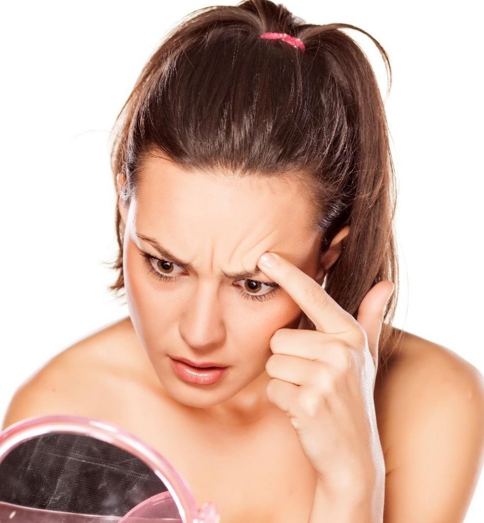 Woman examining her forehead wrinkles.