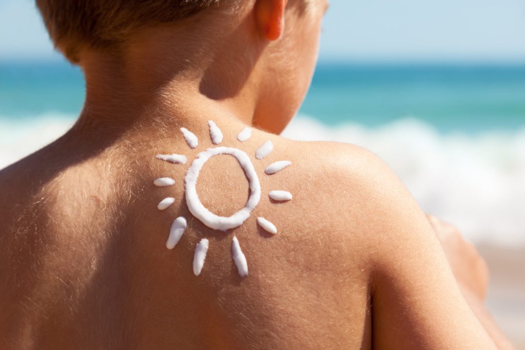 Child with sunscreen applied in the shape of the sun.