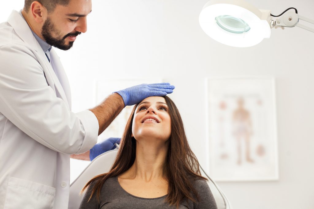 Woman having face examined by medical professional.