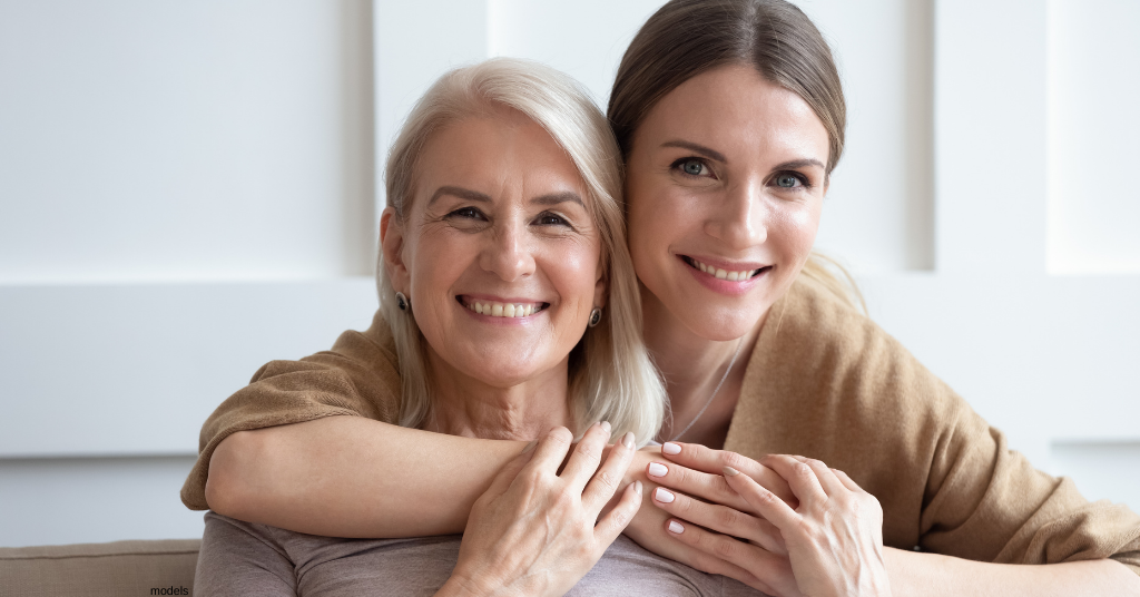 Mother and adult daughter embracing and smiling