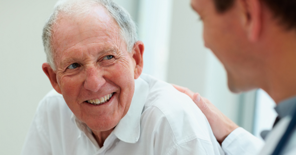 Elderly male patient comforted by compassionate doctor