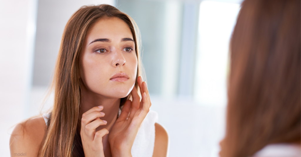 Woman looking at facial scars from acne