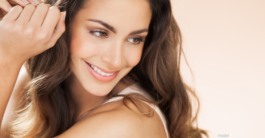 brunette woman smiling with glowing skin (model)