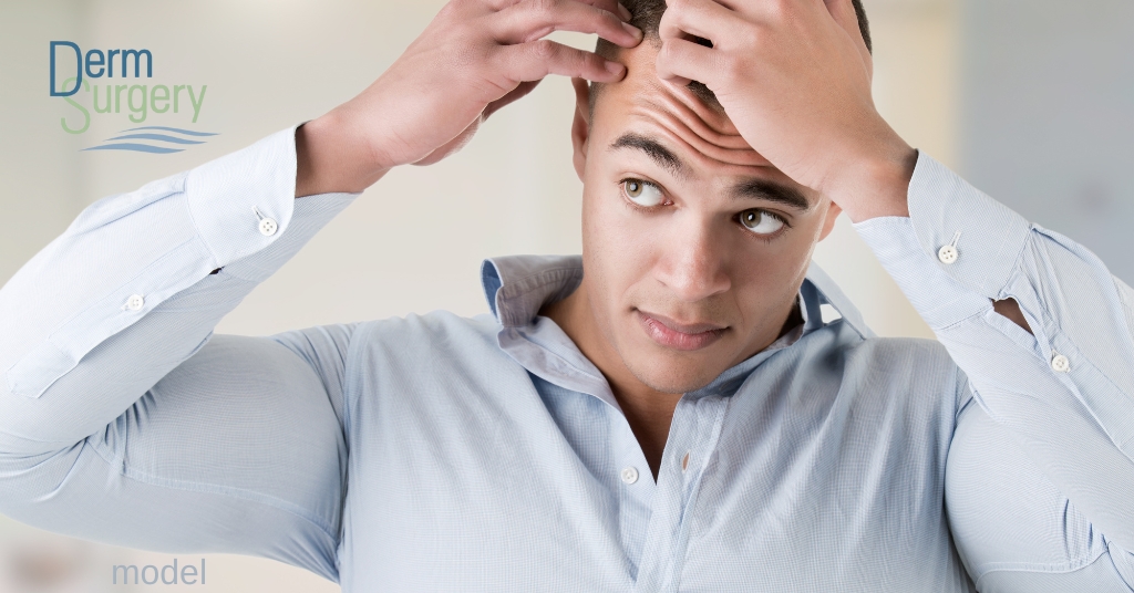 Image of man checking his thinning hair in mirror (model)