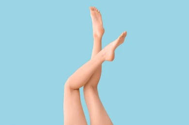 Woman raises her legs in front of a light blue wall.